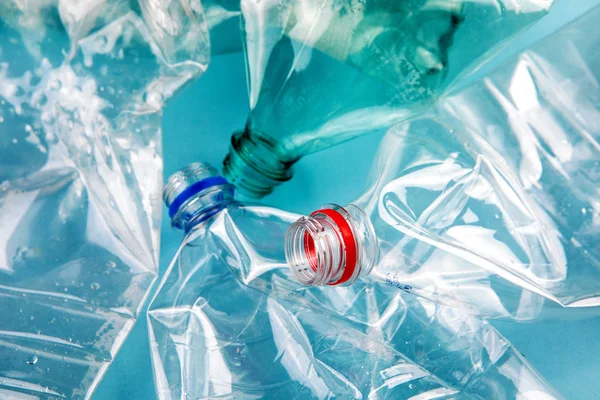 Zgniecione plastikowe butelki na niebieskim tle. Plastikowe śmieci. — Zdjęcie stockowe