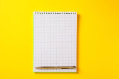 Gümüş kalemin üzerindeki beyaz açık not defteri sarı sırtında izole edilmiş.
