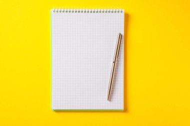 Gümüş kalemin üzerindeki beyaz açık not defteri sarı sırtında izole edilmiş.