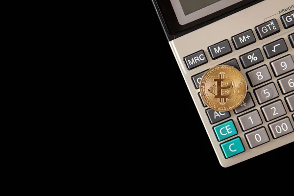 Golden bitcoin coin on calculator close up isolated on black bac — Stock Photo, Image