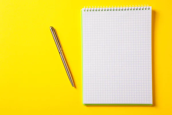 De witte open notitieblok op zilveren pen geïsoleerd op de gele rug — Stockfoto
