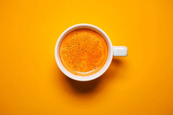 Schwarzer Kaffee in einer Tasse auf orangefarbenem Hintergrund — Stockfoto