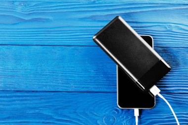 powerbank charges smartphone isolated on blue wood background