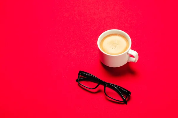 Tasse Kaffee und Brille isoliert auf rotem Hintergrund. Büro — Stockfoto