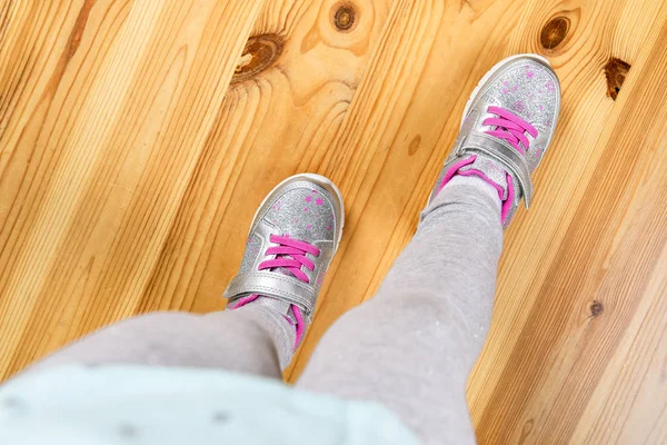 Child in sneakers on wooden background — Stockfoto