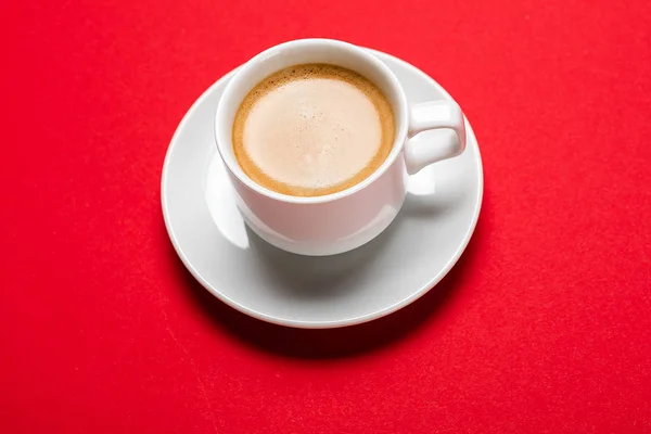 Schwarzer Kaffee in einer Tasse auf rotem Hintergrund — Stockfoto