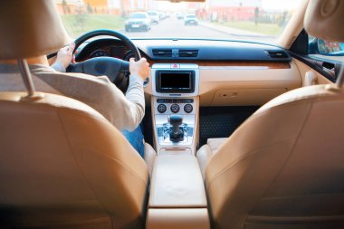 Genç adam asfalt yolda modern arabayı kullanıyor.