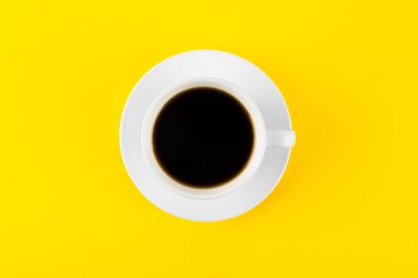 Sarı arka planda bir fincanda koyu kahve.