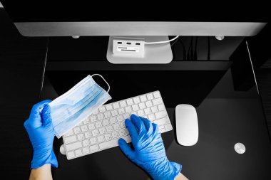 Coronavirus. İş yerindeki dizüstü bilgisayarın yanında bir tıbbi maske var..