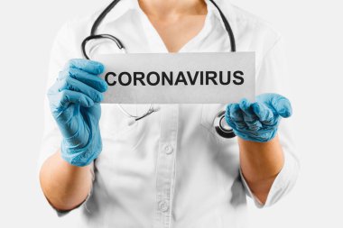 Coronavirus, üzerinde Coronavirus yazan beyaz kart beyaz önlüklü ve eldivenli doktorun ellerinde.. 