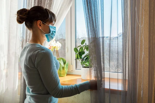 仮面の少女が窓の外を見てる コロナウイルスと隔離の概念 — ストック写真