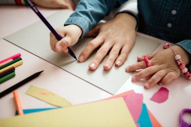 Çocuklu bir anne masada oturur ve ödev yapar. Çocuk evde öğreniyor. Evde eğitim.