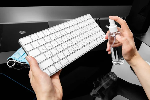 disinfection of a computer keyboard with an antiseptic. Disinfecting workplace concept.