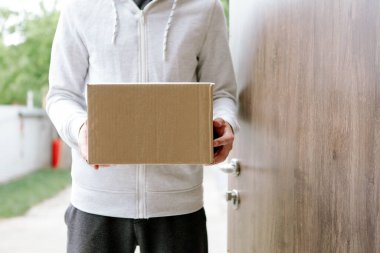 Eldiven takan ve koruyucu maske takan teslimatçı adam eve paket getiriyor..