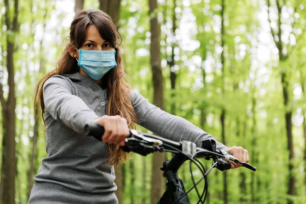 woman in medical mask rides a bicycle in the park