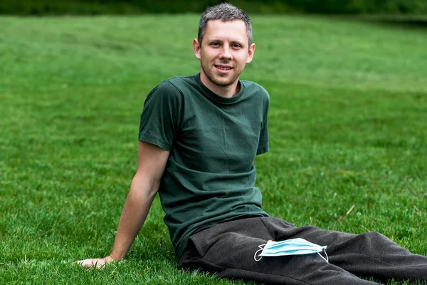 Tabiat maskeli bir adam. Adam COVID-19 karantinasından sonra parkta dinleniyor.