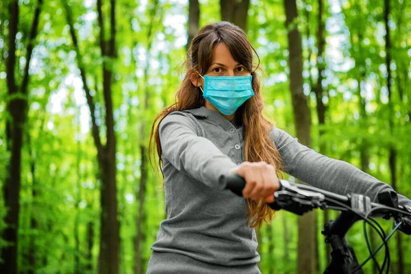 woman in medical mask rides a bicycle in the park