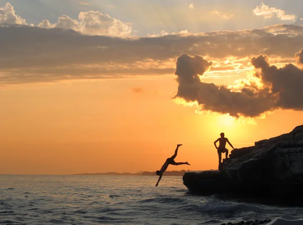 少年たちは、海岸の崖からジャンプします。 — ストック写真