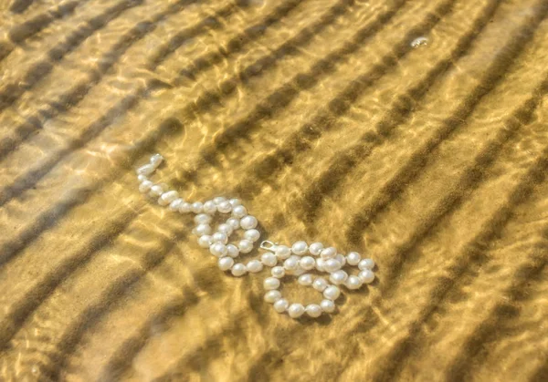 Μαργαριτάρι χάντρες πάνω στην άμμο της θάλασσας — Φωτογραφία Αρχείου