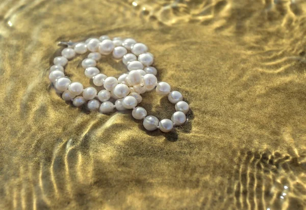 Pearl beads on the sea sand — Stock Photo, Image