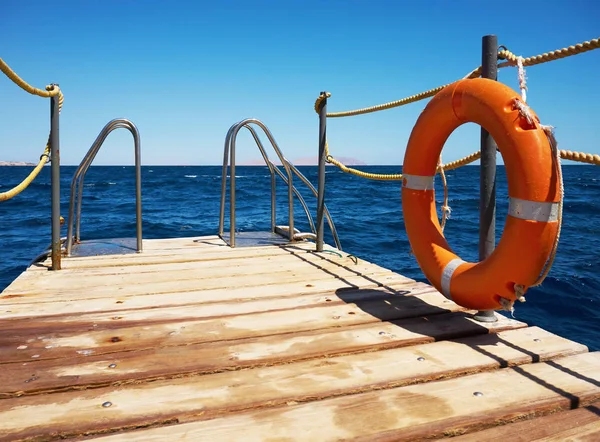 Wooden pier near the sea with lifebuoy — Stock Photo, Image