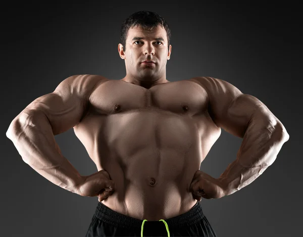 Vacker muskulös bodybuilder poserar över svart bakgrund. — Stockfoto