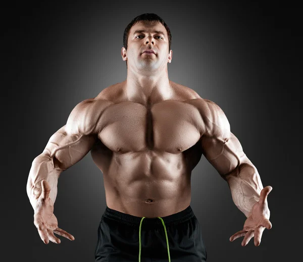 Handsome muscular bodybuilder posing over black background. — Stock Photo, Image