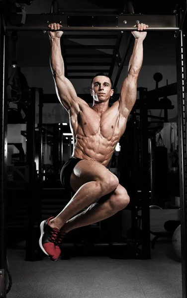 Спортсмен мускулистый фитнес-модель тянет вверх на горизонтальной полосе — стоковое фото