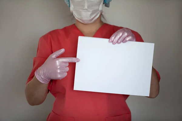 Femme médecin portant des gants et un masque de protection, tenant du papier vide . — Photo