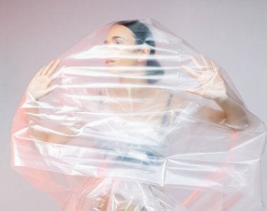 Plastik filmden yapılmış elbise giymiş bir kız. Covid19 Moda Portresi.