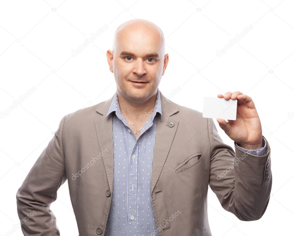 A bald man in a beige suit shows a business card isolated on white.