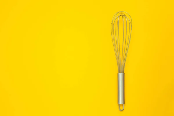 Metal whisk for whipping on a yellow background. — Stock Photo, Image