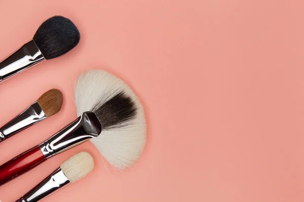 Conjunto de escovas para aplicar cosméticos em um fundo rosa — Fotografia de Stock