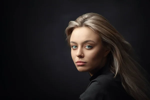 Dramatische studio portret van mooie jonge vrouw op donkere achtergrond. — Stockfoto