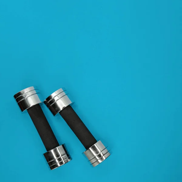 Metal small dumbbells on a blue background. — Stock Photo, Image