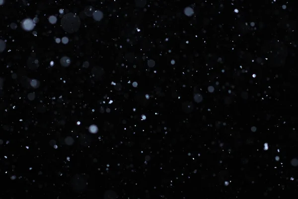 Nieve real cayendo sobre un fondo negro para su uso como capa de textura en su proyecto. Añadir como "aligerar" Capa en Photoshop para añadir nieve que cae a cualquier imagen. Ajustar la opacidad al gusto . — Foto de Stock