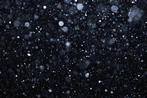 Schneesturm. Bokeh-Lichter auf schwarzem Hintergrund, Schuss fliegender Schneeflocken in der Luft — Stockfoto