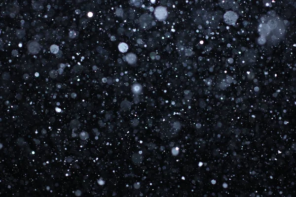 Texture tempête de neige. Bokeh lumières sur fond noir, plan de flocons de neige volants dans l'air — Photo