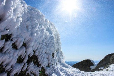 Kış Peyzaj taş Rock ile karla kaplı. Kiriş mavi gökyüzünde güneş'in kar fırtınasında.