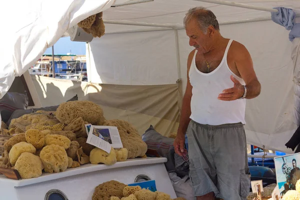 CHANIA, CRETE - SEPTEMBER 03, 2014 -The gray-haired man sells corals on souvenirs from the boat. Chania, Crete, Greece, Europe, September 03, 2014. — Stock Photo, Image