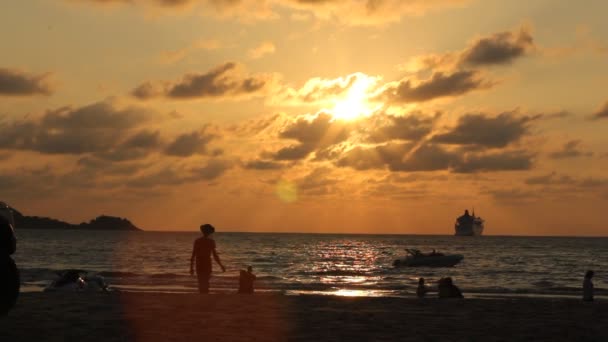 PHUKET, THAILAND - MARCH 14, 2017: Sunset on Patong beach. Crowds of tourists walking and swimming on one of the famous Phuket beach Patong. — Stock Video