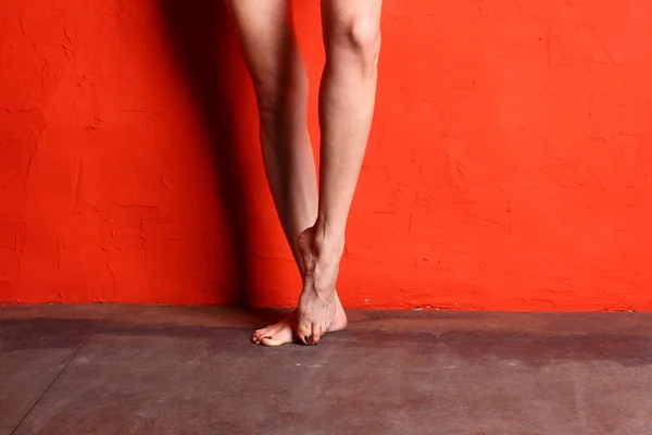 赤い壁の背景に裸の女性バレリーナの脚 — ストック写真