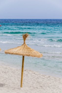 Kumsalda saman şemsiyesi ve açık gökyüzü.