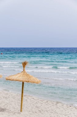 Kumsalda saman şemsiyesi ve açık gökyüzü.