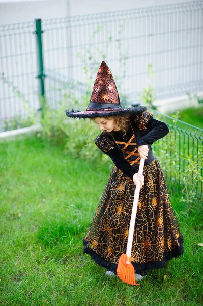 Vorbereitung auf Halloween. das Mädchen im Anzug der bösen Hexe reinigt eine Rasenharke — Stockfoto