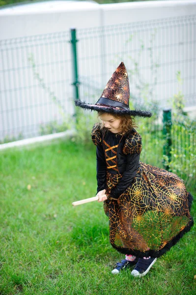 Voorbereiding voor Halloween. Het meisje in een pak van de boze heks pretendeert dat ze vliegt op de bezem. — Stockfoto