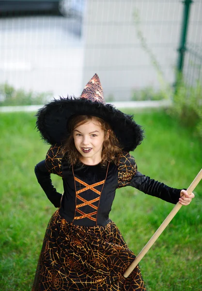 Vorbereitung auf Halloween. das Mädchen im Anzug der bösen Hexe reinigt eine Rasenharke — Stockfoto