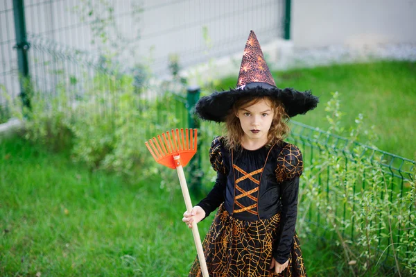 Vorbereitung auf Halloween. das Mädchen im Anzug der bösen Hexe reinigt eine Rasenharke — Stockfoto
