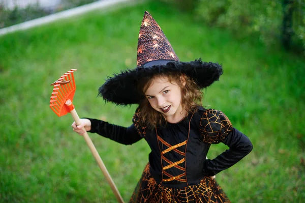 Voorbereiding voor Halloween. Het meisje in pak van de boze heks reinigt een gazon hark — Stockfoto