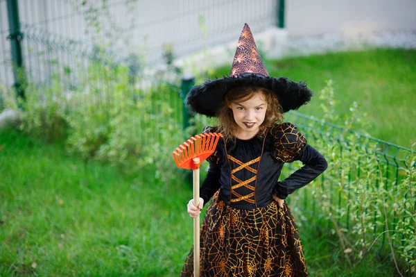 Voorbereiding voor Halloween. Het meisje in pak van de boze heks reinigt een gazon hark — Stockfoto